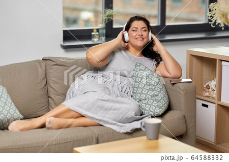 woman in headphones listening to music at home woman in headphones listening to music at home 64588332