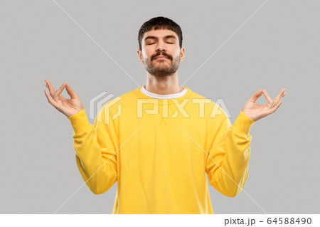 young man in yellow sweatshirt meditating young man in yellow sweatshirt meditating 64588490
