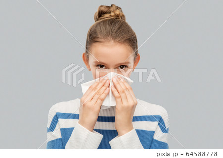 sick teenage girl blowing nose with paper tissue 64588778