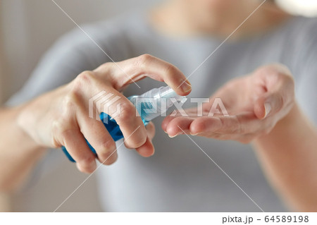 close up of woman spraying hand sanitizer 64589198