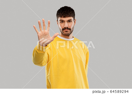 serious young man showing stop gesture 64589294