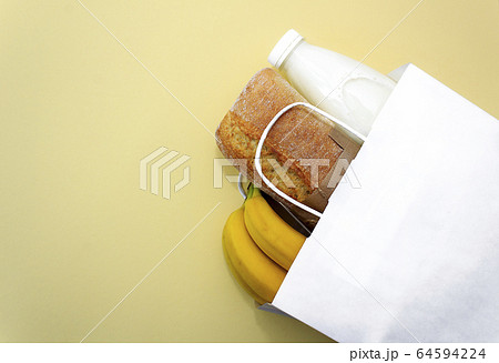 Donation food. Corn, buckwheat, bananas, milk, bread in white bag on yellow background. Donation food. Corn, buckwheat, bananas, milk, bread in white bag on yellow background. 64594224