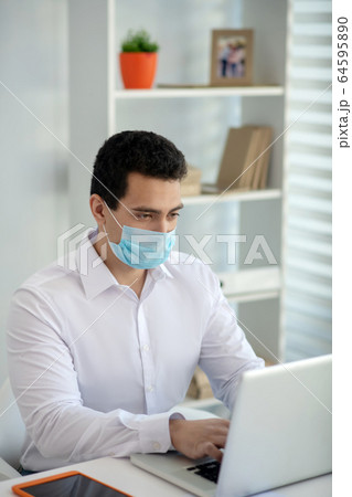 Man in a protective mask looking concentrated while working 64595890