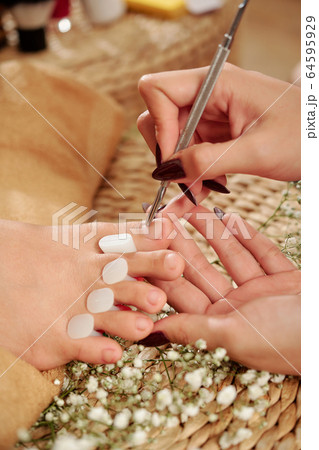Pedicurist pushing cuticle 64595929