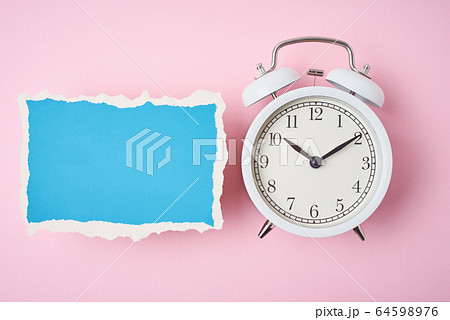 White alarm clock and empty torn paper sheet on a White alarm clock and empty torn paper sheet on a 64598976