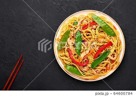 Chicken Lo Mein Noodles in white plate at dark slate backdrop 64600784