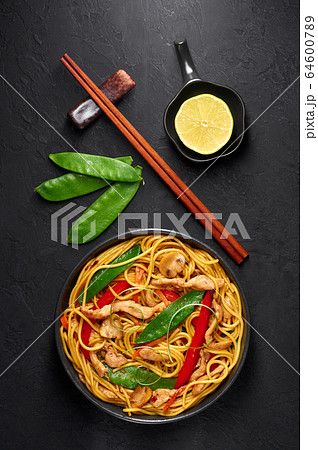 Chicken Lo Mein Noodles in black bowl at dark slate backdrop 64600789