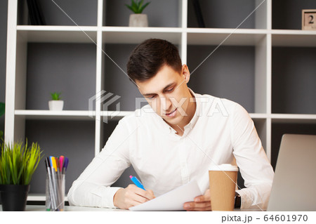 Businessman sitting at office desk working on laptop computer Businessman sitting at office desk working on laptop computer 64601970