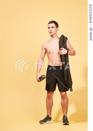 Young athlete man with rug and a rope in studio Young athlete man with rug and a rope in studio 64603329