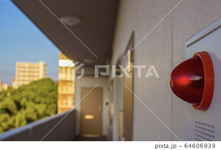 A close up of a red warning light in front of an apartment building in Japan. 64606939