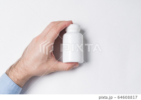 White plastic Pill Bottle in male hand. medicine 64608817