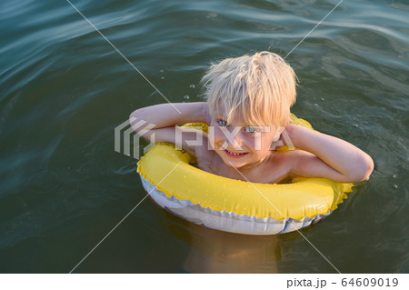 Blond boy swims with yellow floaties. Vacation sea 64609019