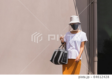 Woman in face shield with hat and protective mask covid-19 spreading. 64612428