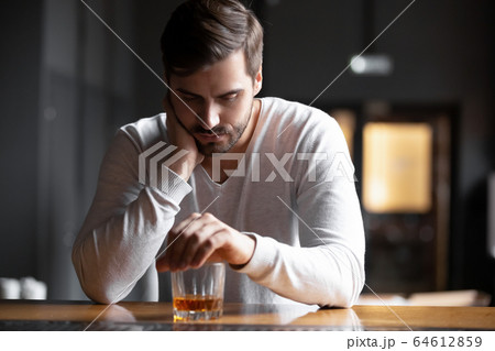 Upset man drinker alcoholic sitting with glass drinking whiskey alone Upset man drinker alcoholic sitting with glass drinking whiskey alone 64612859