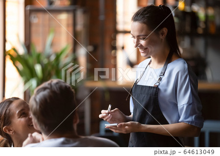 Smiling female waitress take order talk to clients couple 64613049