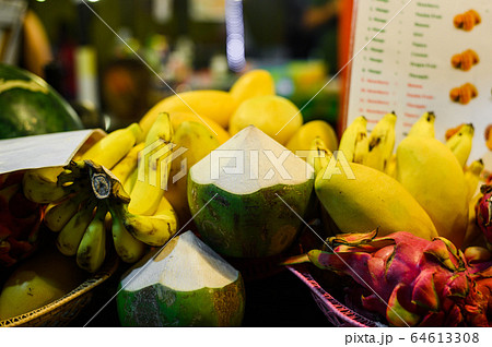 Tropical thai fruits stall at local food market in Thailand. Coconut, dragonfruit, banana and mango at night fair. Tropical thai fruits stall at local food market in Thailand. Coconut, dragonfruit, banana and mango at night fair. 64613308