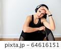 Sporty woman with headphones tired after workout 64616151