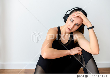 Sporty woman with headphones tired after workout 64616151