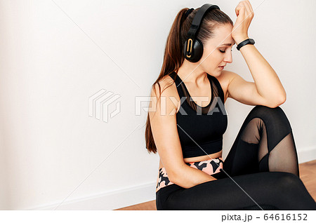 Sporty woman with headphones tired after workout 64616152