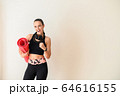 Sporty woman with headphones and rolled mat 64616155