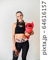 Sporty woman with headphones and rolled mat 64616157