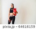 Sporty woman with headphones and rolled mat 64616159