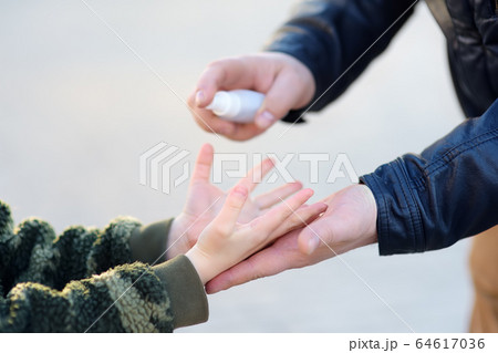 Mature man and little child makes disinfection 64617036