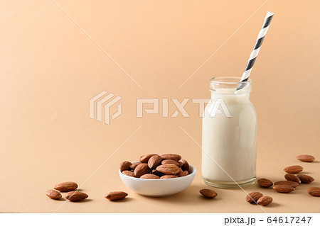 Fresh almond milk in glass bottle on beige. Fresh almond milk in glass bottle on beige. 64617247