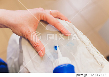 Hand Laundry worker in the process of removing stains by using a special dry-cleaning. 64617378