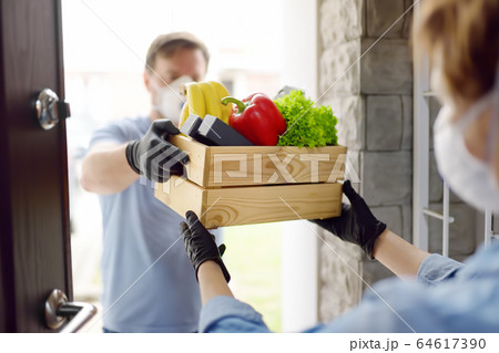 Courier or volunteer delivering shopping to woman Courier or volunteer delivering shopping to woman 64617390