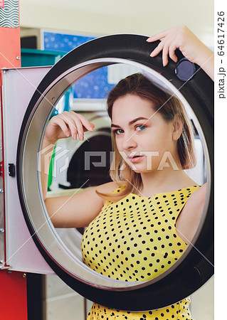Beautiful young woman is sitting on the floor near washing machine. Beautiful young woman is sitting on the floor near washing machine. 64617426