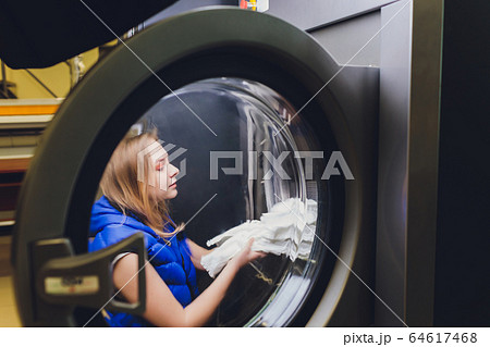 Hands to load the Laundry in the washing machine at the dry cleaners. 64617468