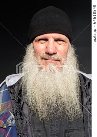 Face of mature bearded hipster man against black wall outdoors Face of mature bearded hipster man against black wall outdoors 64618849