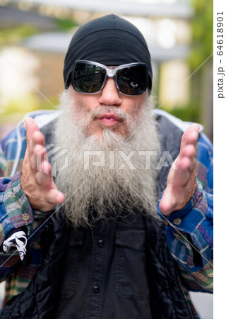 Face of mature bearded man with sunglasses blowing kiss outdoors 64618901