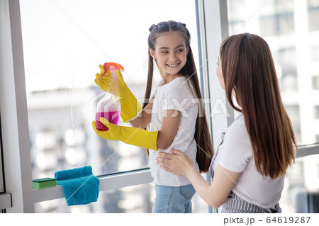 Daughter with cleanser and mom standing nearby. 64619287