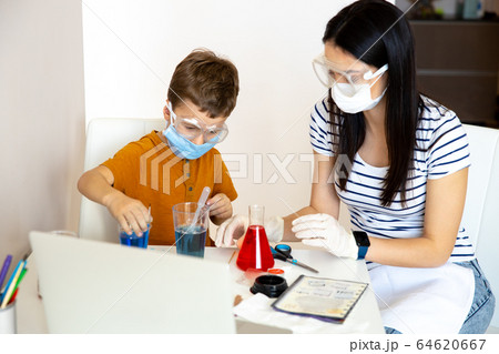 Serious young brunette helping her son with experiment Serious young brunette helping her son with experiment 64620667