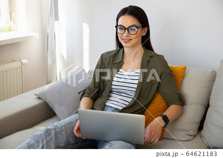 Beautiful young woman working on laptop remotely from home Beautiful young woman working on laptop remotely from home 64621183