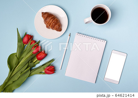 Cup of coffee, croissant, notepad, pen, phone and flowers 64621414