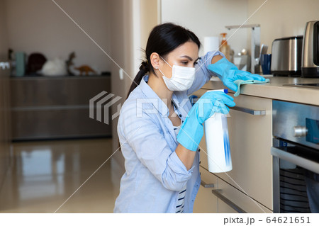 Woman doing household routine with sanitizer in kitchen 64621651