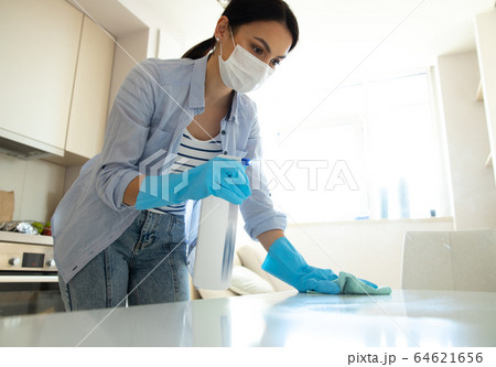 Young woman using spray for cleaning kitchen Young woman using spray for cleaning kitchen 64621656