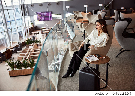 Beautiful young woman sitting in chair in departure lounge 64622154