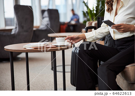 Young woman holding cellphone and grabbing cup of coffee 64622613