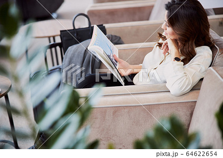 Charming young woman reading book in departure lounge 64622654