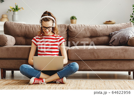 Happy pensive woman using laptop at home. 64622956
