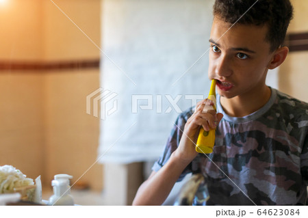 Teenage Boy brushing teeth with electric toothbrush in Bathroom Teenage Boy brushing teeth with electric toothbrush in Bathroom 64623084