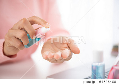 Closeup woman hands using alcohol spray to her Closeup woman hands using alcohol spray to her 64626468