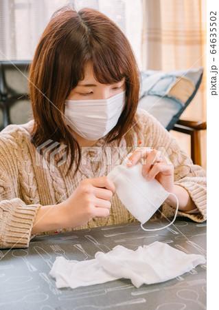 子供用マスクに紐を通す女性　手作り　感染症対策 64635502
