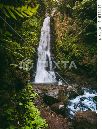 Waterfall in tropical jungle and alone woman. Waterfall in Bali, Indonesia 64636116