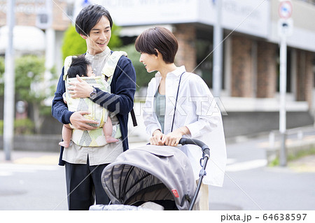 生後三ヶ月の赤ちゃんと散歩する父母の写真素材