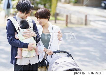 生後三ヶ月の赤ちゃんと散歩する父母の写真素材